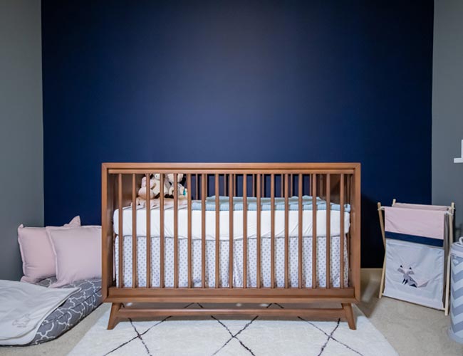 modern nursery, nursery inspo, baby room inspo, baby room ideas, nursery ideas, blinds galore, roman shades nursery, pink bookcase, walnut crib, stylish nursery chair, nursery decor ideas, navy blue nursery, navy blue baby room, gender neutral baby room, midcentury modern baby room